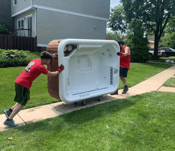 2 technicians removing a hot tub on a dolly